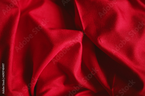 Crumpled red satin fabric, rumpled bed after waking up in the morning, fabric design. Copy space on textiles.