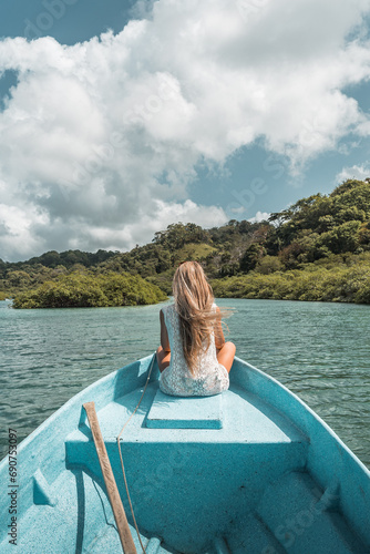 Blonde woman sitting on the edge of a boat floating
