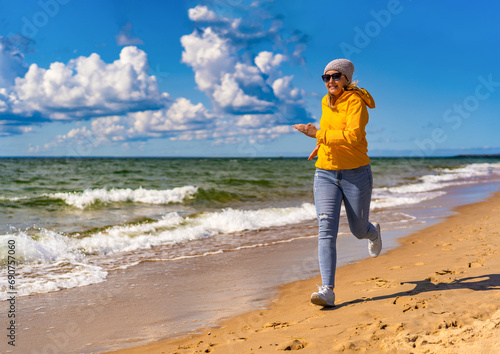 Beautiful mid adult woman running on sunny beach