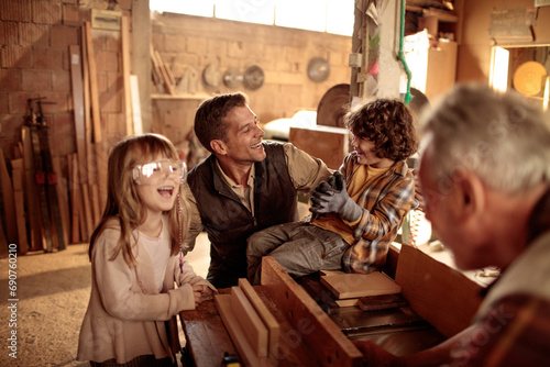 Cute little children working with older carpenters in workshop