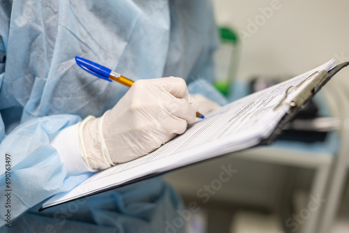 Close-up The anesthesiologist records the progress of the operation on a tablet while standing in the operating room Wearing an operating gown the anesthesiologist describes the operation in a chart. photo