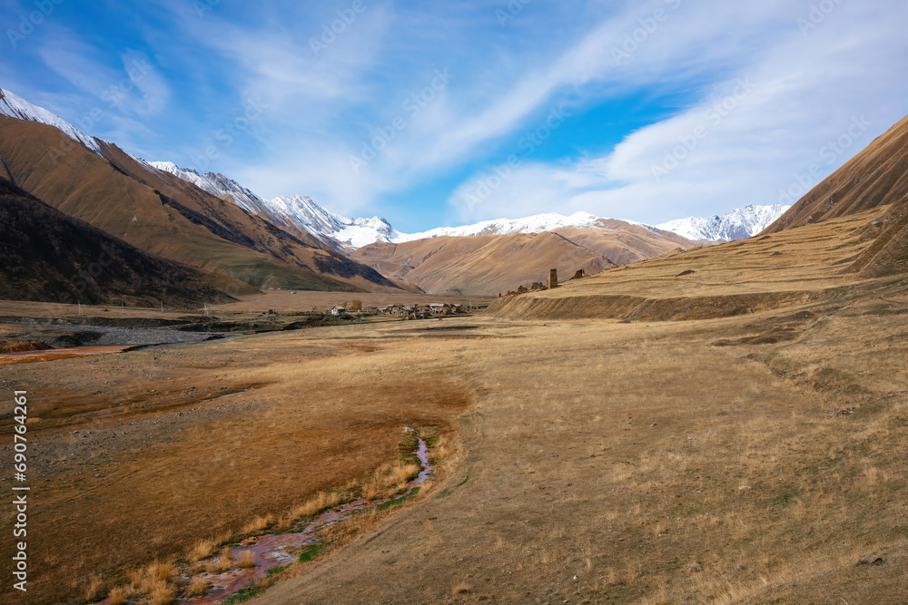 Expansive Alpine Valley with Snow-Capped Peaks, Rustic Village Amidst Autumn Colors