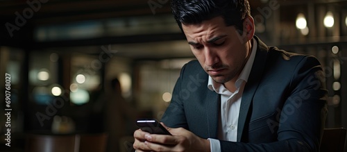 Upset and sad man at workplace inside office businessman at work received notification message negative hispanic reading bad news online from smartphone. Copyspace image. Square banner