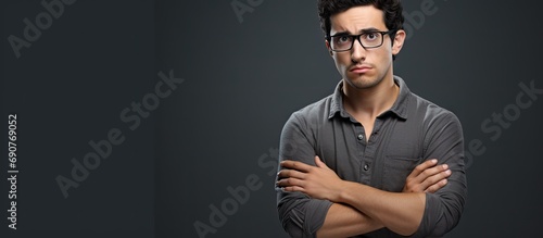 Young hispanic man wearing casual clothes and glasses skeptic and nervous disapproving expression on face with crossed arms negative person. Copyspace image. Header for website template photo