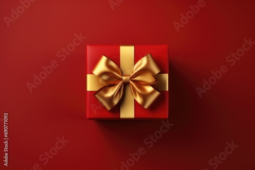 A red gift box with a gold bow on a red background. Perfect for holiday and celebration themes © Fotograf