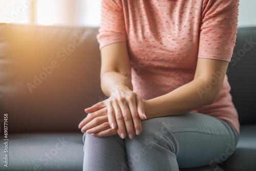 A woman is depicted sitting on a couch with her hands resting on her knees. This image can be used to portray relaxation  contemplation  or introspection