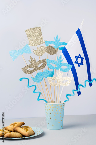 Purim celebration concept. Masks, bow, hat, mustached on a stick with the Jewish flag. Festive pastries hamans ears photo