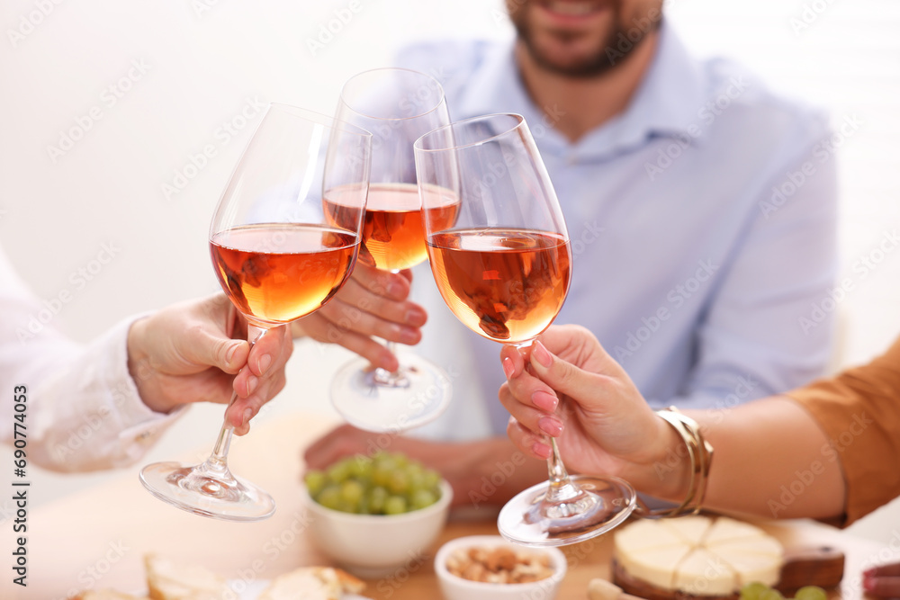 People clinking glasses with rose wine above table, closeup People clinking glasses with rose wine above table, closeup