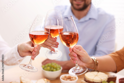 People clinking glasses with rose wine above table, closeup