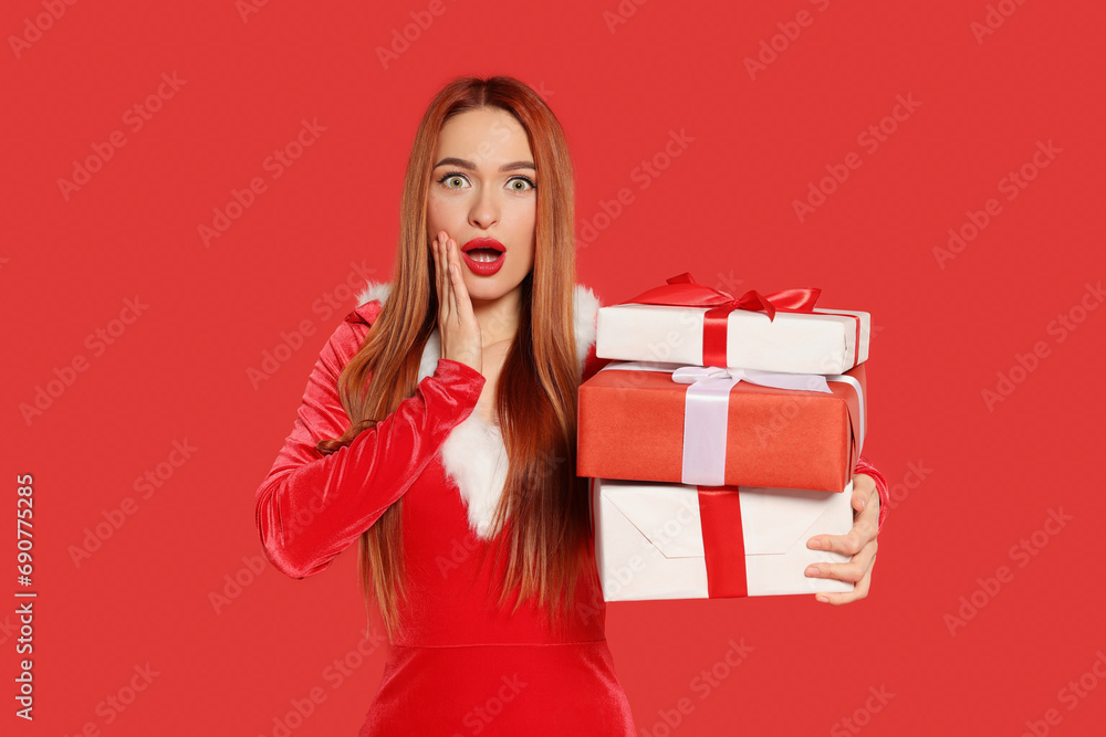 Emotional young woman with Christmas gifts on red background Emotional young woman with Christmas gifts on red background