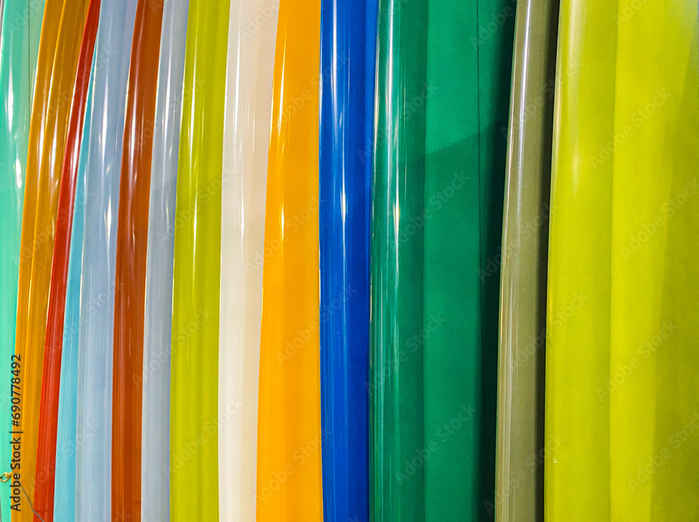Horizontal coseup of colorful surfboards stacked together in a rainbow of colors.