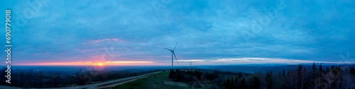 Morning sun on electric windmills, wind wheels with energy support in the west in the foothills. Panorama for banner.