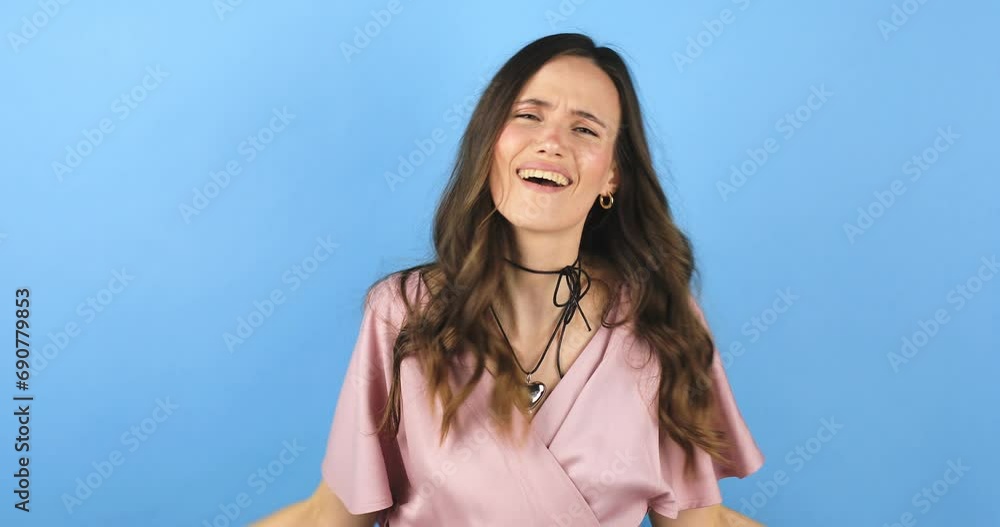 Young pathos woman pointing cheerfully while giving her imaginary money, in front of a blue background. The concept of pouring money without thinking. It makes it rain by throwing money into the air. Young pathos woman pointing cheerfully while giving her imaginary money, in front of a blue background. The concept of pouring money without thinking. It makes it rain by throwing money into the air.