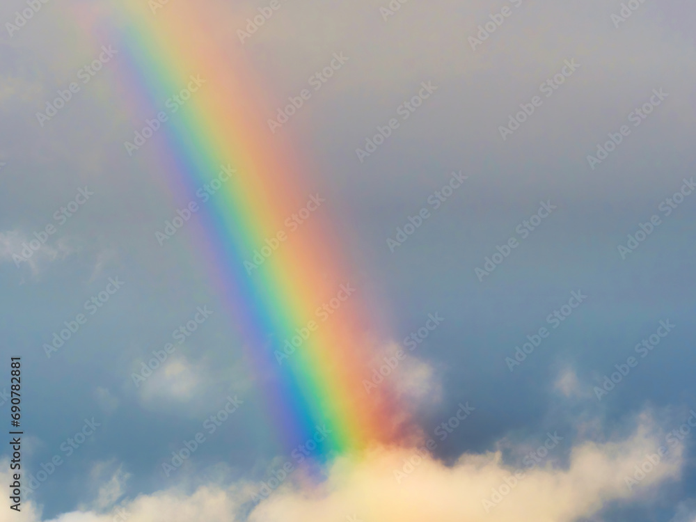 A bright rainbow shining through stormy cumulonimbus clouds during unsettled weather above the jurassic coastline on a December morning