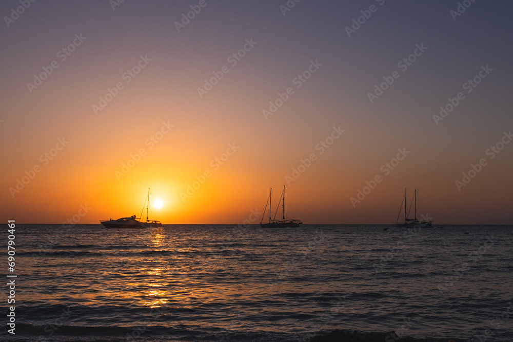 Three Sailboats at Sunset.