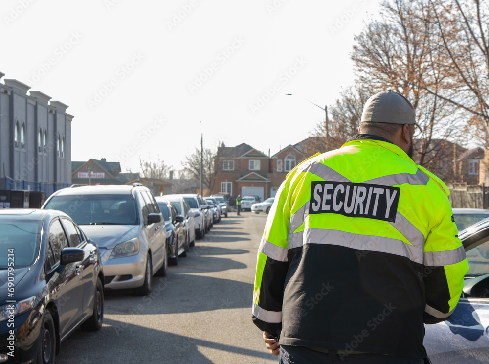 Fototapeta premium Security guard conducting access control, traffic control, and parking enforcement duties around a community building.