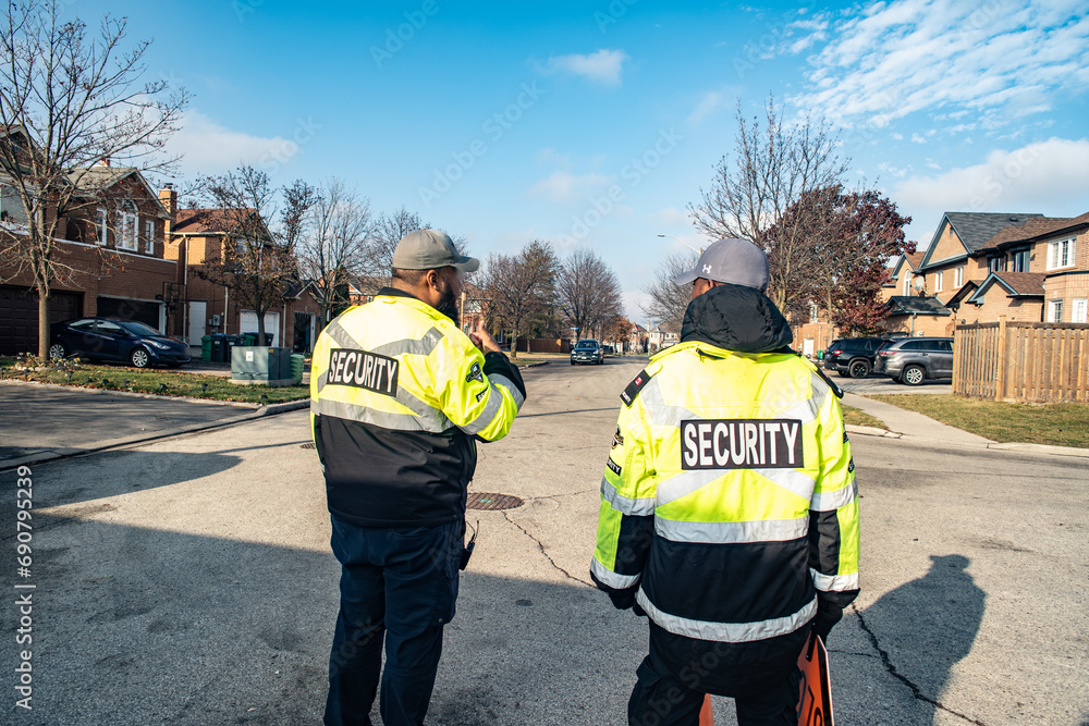 Obraz premium Security guard conducting access control, traffic control, and parking enforcement duties around a community building.