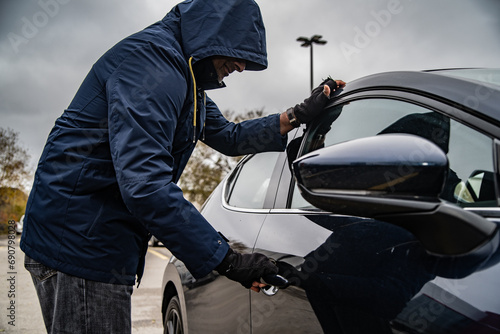 A car thief is breaking into a car in broad daylight in Toronto, Ontario, Canada.