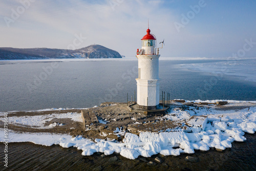 Aerial view of the lighthouse in winter in the ice at dawn