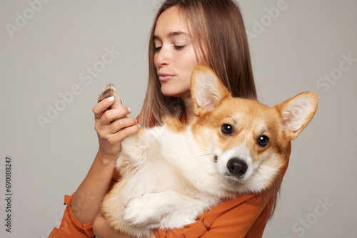 brunette girl kisses the paw of a corgi dog on a clean light background, Animal love concept
