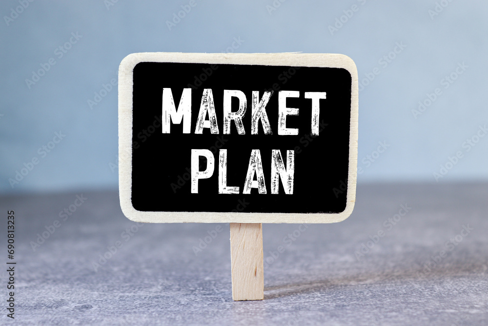 Marketing Plan written on note pad, office desk with electronic devices, computer and paper, wood table from above