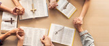 Cropped image of group of people praying together while holding hand on holy bible book at wooden church. Concept of hope, religion, faith, christianity and god blessing. Top view. Burgeoning.