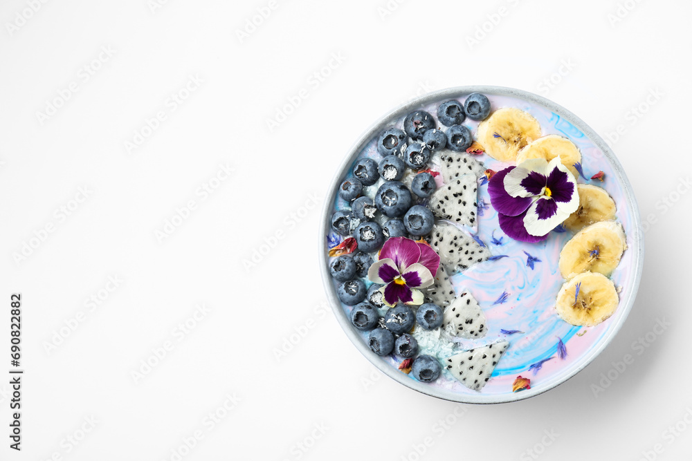 Delicious smoothie bowl with fresh fruits, blueberries and flowers on white background, top view. Space for text