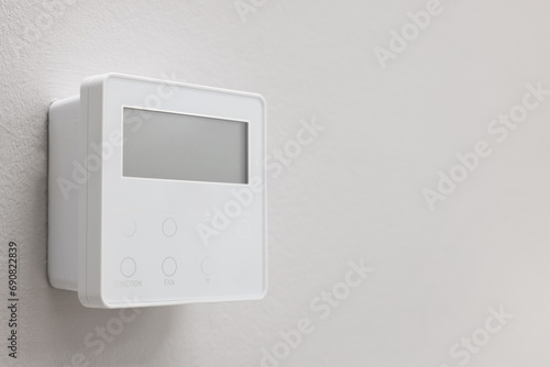 One thermostat on white wall, space for text. Smart home system