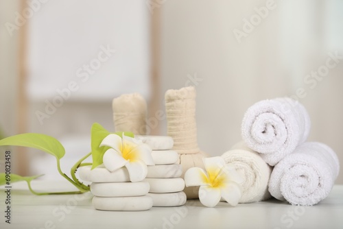 Composition with different spa products and plumeria flowers on white table