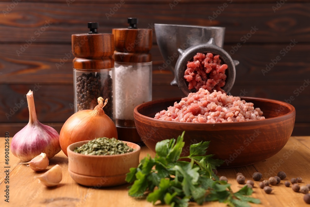 Manual meat grinder with beef mince, spices and parsley on wooden table Manual meat grinder with beef mince, spices and parsley on wooden table