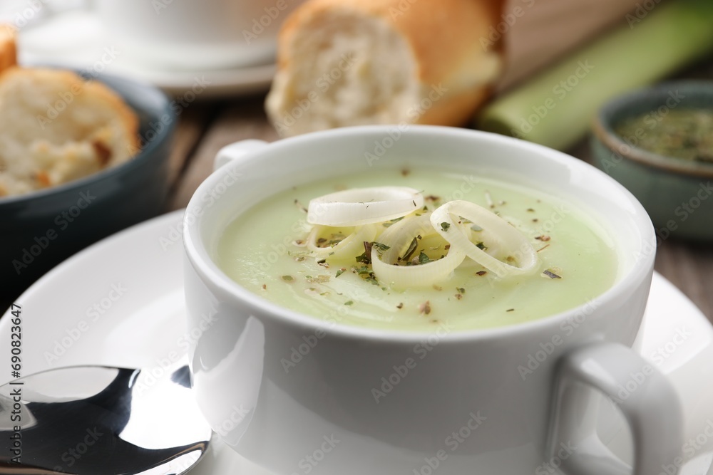 Delicious cream soup with leek and spices in bowl on table, closeup Delicious cream soup with leek and spices in bowl on table, closeup