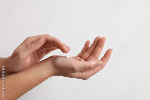 Woman applying cosmetic cream onto hand on white background  closeup