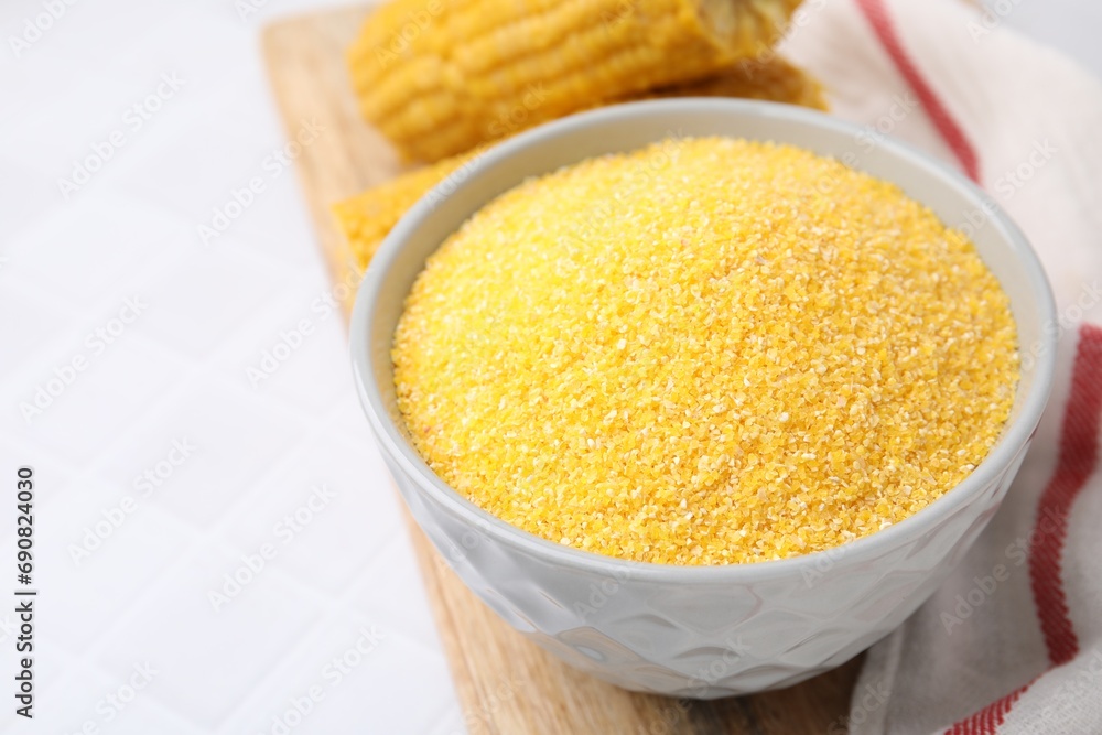 Raw cornmeal in bowl on white table, closeup. Space for text Raw cornmeal in bowl on white table, closeup. Space for text