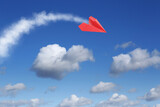 Red paper plane flying in blue sky with clouds