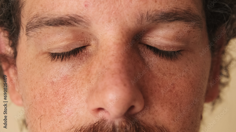 Detailed close-up shot of man with closed eyes studio on beige background