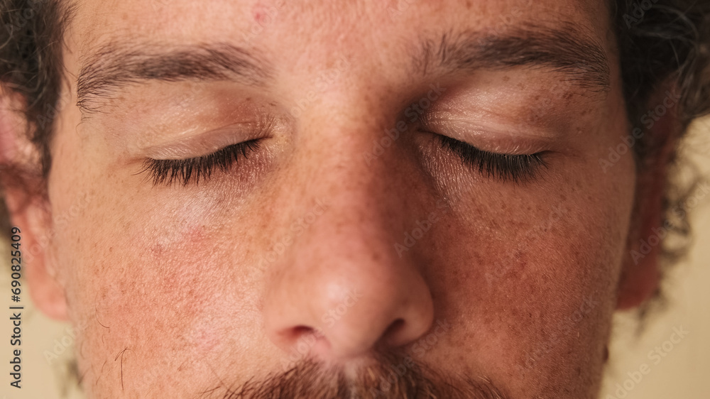 Obraz premium Detailed close-up shot of man with closed eyes studio on beige background