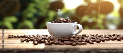 White cup filled with roasted coffee beans falls sideways on wooden table blurring the background of the coffee bean garden