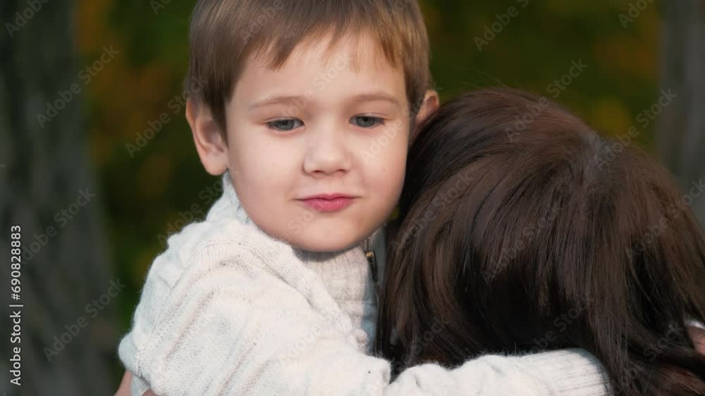 Mother in heart of colourful park stands with cute son cradled in arms