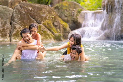 Group of Young Asian man and woman enjoy and fun outdoor lifestyle travel nature forest mountain on summer holiday vacation. Happy generation z people friends playing water together at waterfall.