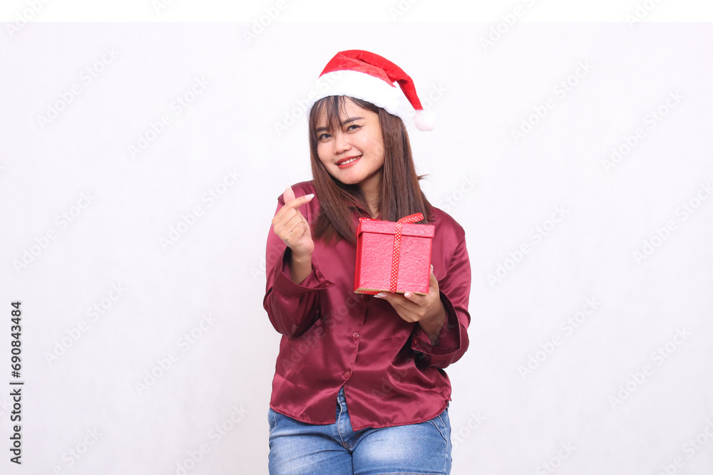 Photo portrait of beautiful Asian girl in her 20s carrying boxed gifts in Christmas Santa Claus hat modern shiny red shirt outfit sign of happy love on white background for promotion and advertising Photo portrait of beautiful Asian girl in her 20s carrying boxed gifts in Christmas Santa Claus hat modern shiny red shirt outfit sign of happy love on white background for promotion and advertising