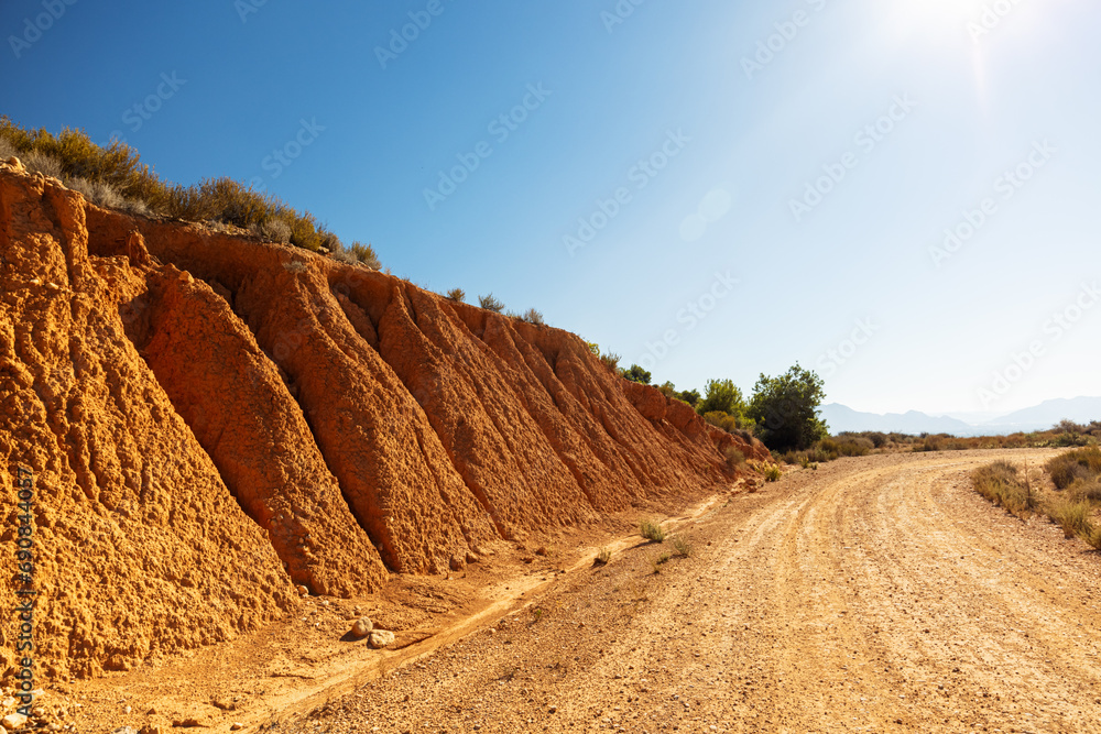 Long dusty road isolated and distant desert hills and valleys with hills rising above the road 