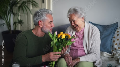 Mature man celebrating with his senior mother at her apartment.