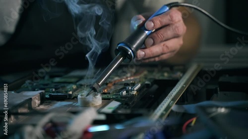 close-up of the soldering tool of a male repairman repairs laptop and soldering electronics in a  appliance repair shop photo