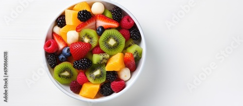 Top-down view of fruit salad in white bowl, copy space available.