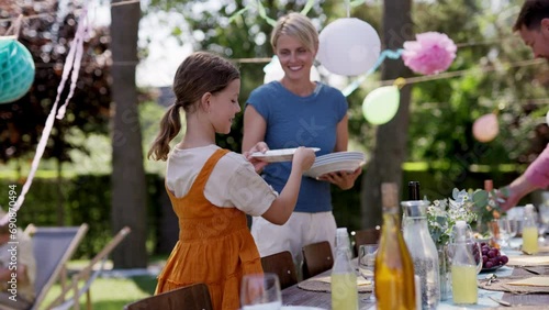 Mother and daughter setting table for summer garden party. photo