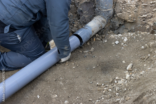 住宅の排水を下水道につなげる配管工事する人物 photo