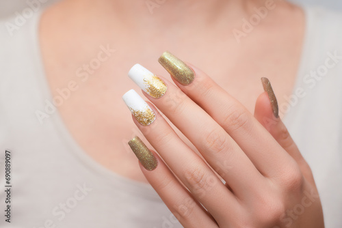 Female hands with long nails with glitter nail polish. Long gold nail design. Women hand with sparkle manicure.