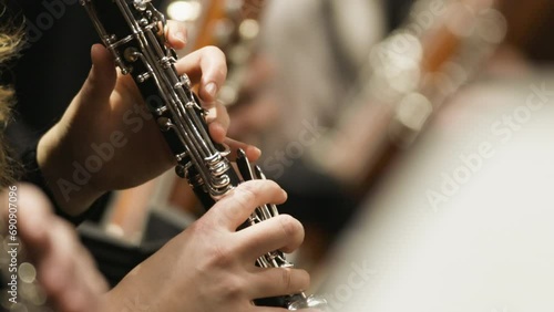 A alow motion clip of a musician playing a clarinet during a live classical symphony orchestra concert in the woodwinds section photo