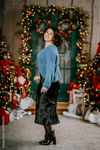 Portrait of a wealthy mature woman with evening make-up and hairstyle posing in a black dress on the background of the Christmas room. Luxurious lifestyle. Christmas holidays concept
