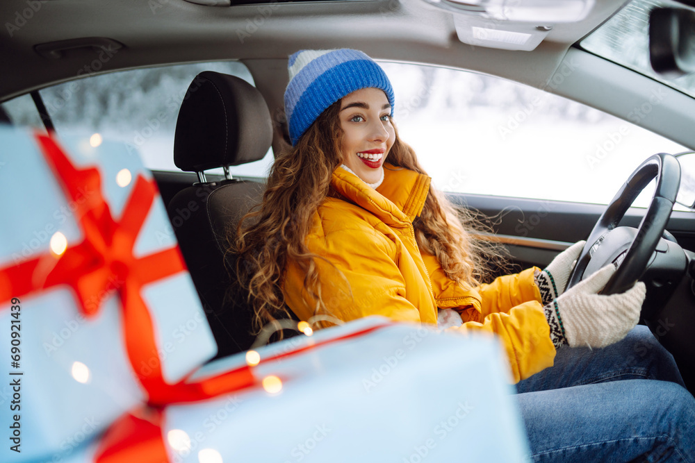 Portrait of a happy woman with bright lipstick in a car, carrying Christmas gifts. Young woman with gift boxes in a car on a snowy road. Holidays concept. Lifestyle. Portrait of a happy woman with bright lipstick in a car, carrying Christmas gifts. Young woman with gift boxes in a car on a snowy road. Holidays concept. Lifestyle.